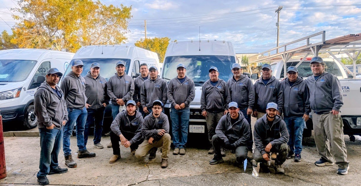 The full E. Costa Plumbing & Gas team gathered in front of the company service vans in West Palm Beach, FL