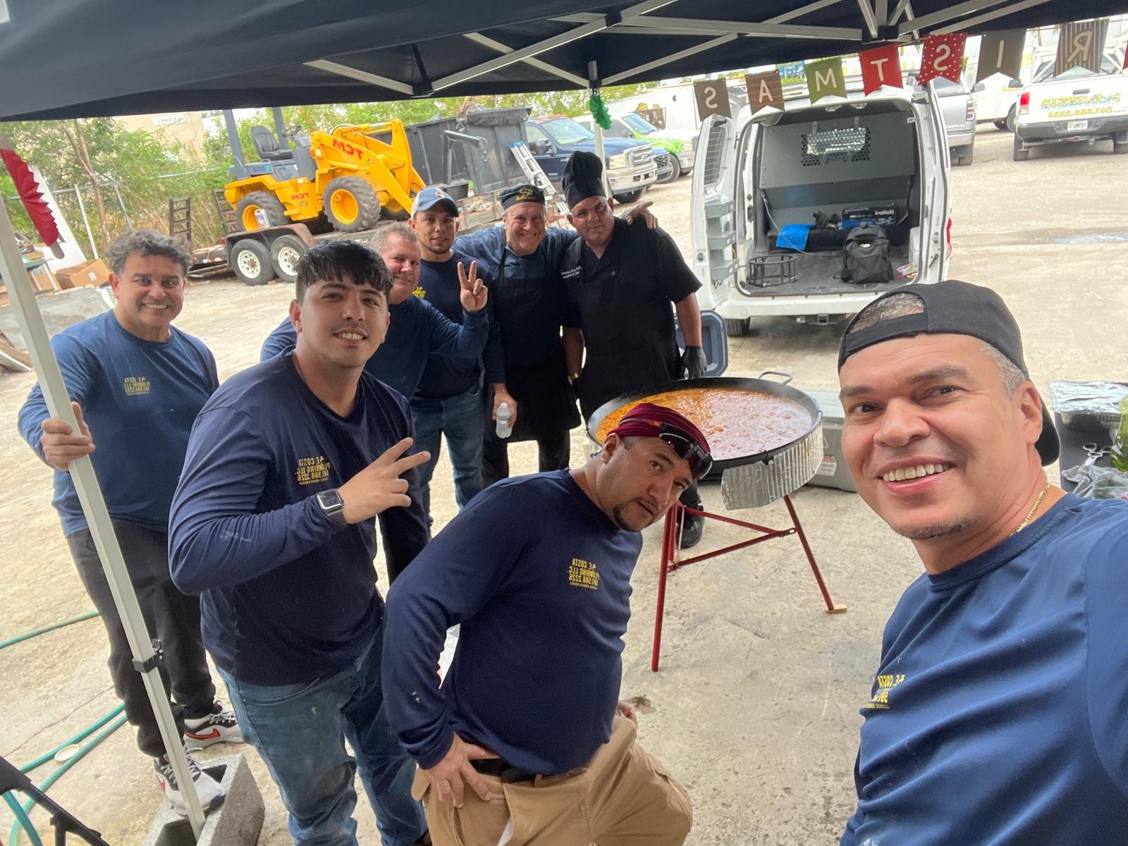 The E. Costa Plumbing team with a giant paella pan at a shop cookout